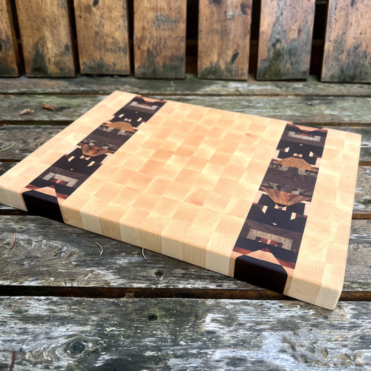 Butcher block cutting board with black and white pattern on a wooden surface