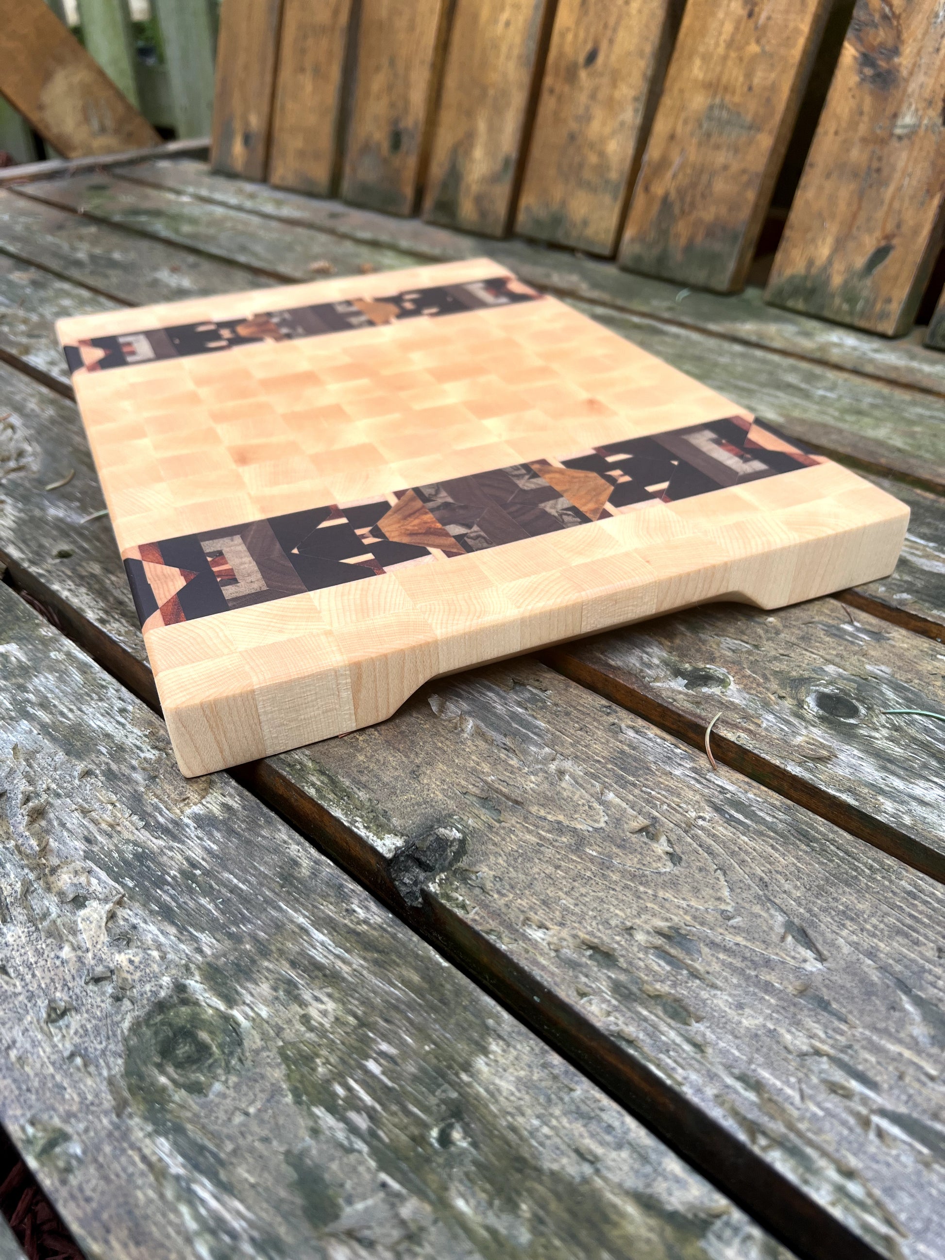 Wooden cutting board with decorative inlay on a wooden surface
