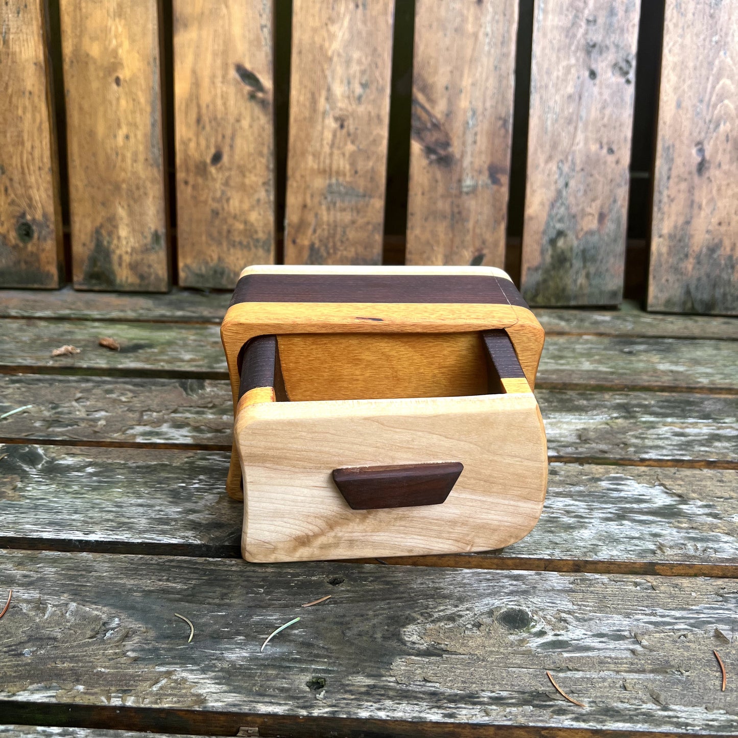 Wooden box with a brown lid and handle on a wooden surface