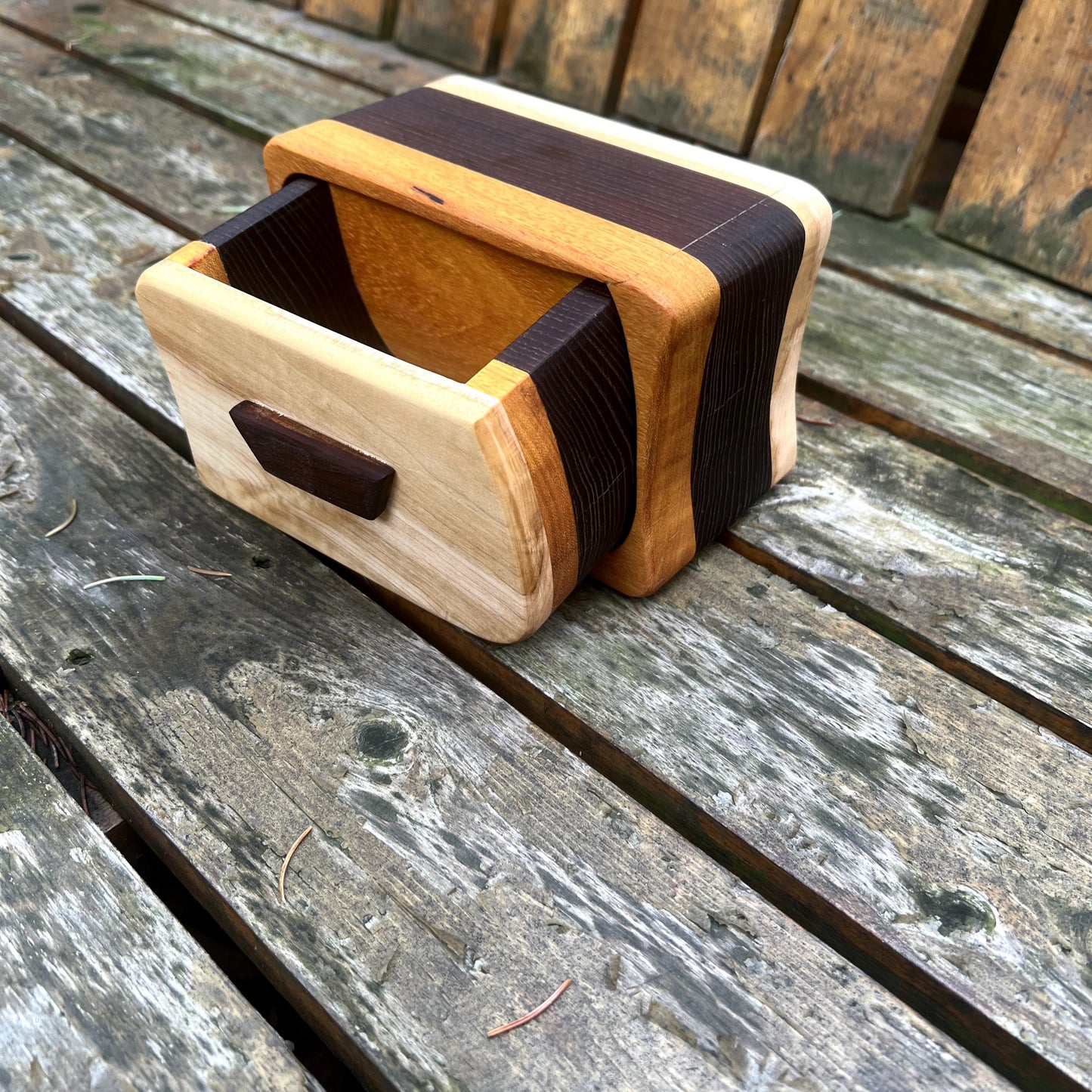 Wooden box with a dark brown band on a wooden surface