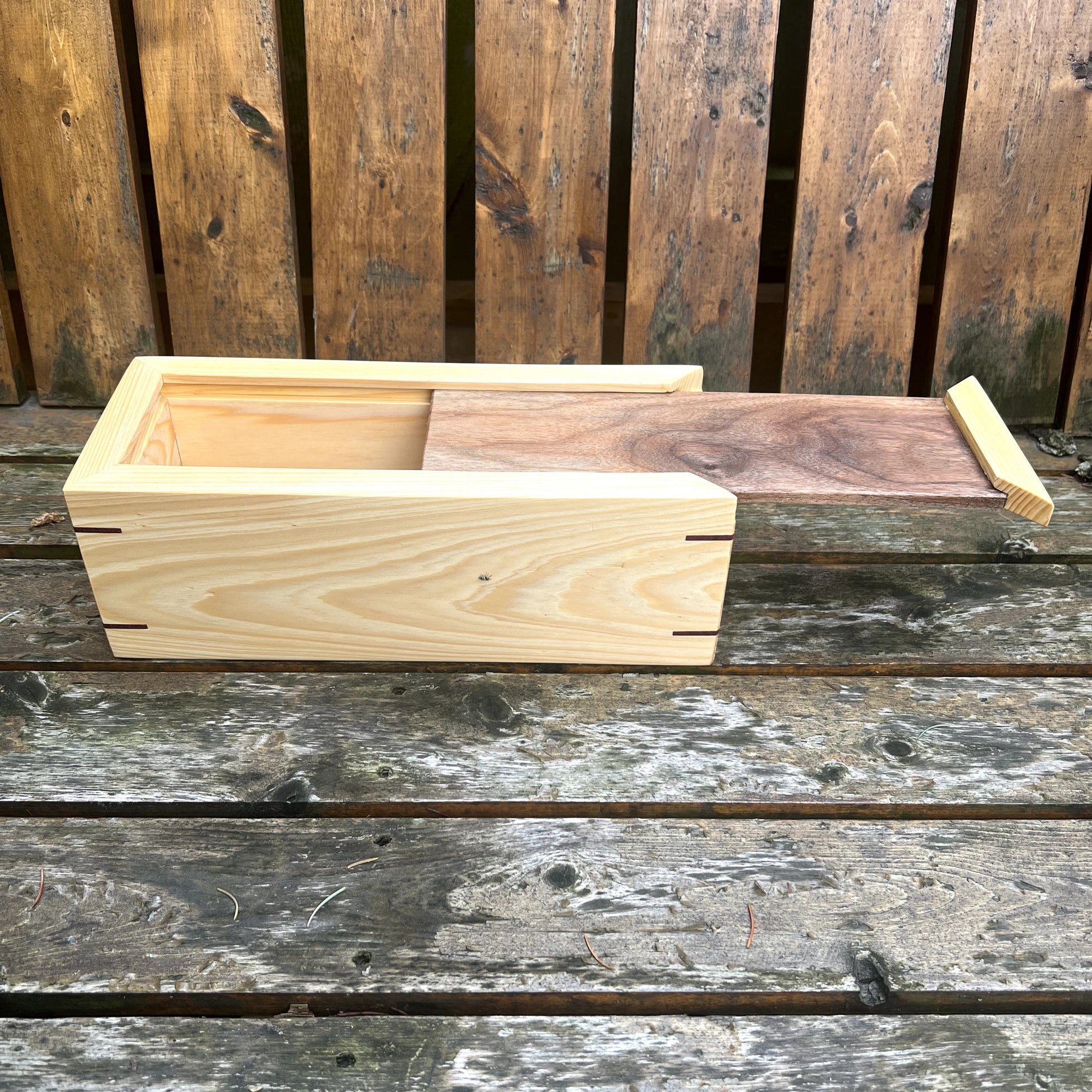 Wooden planter box on a wooden surface with a wooden fence in the background