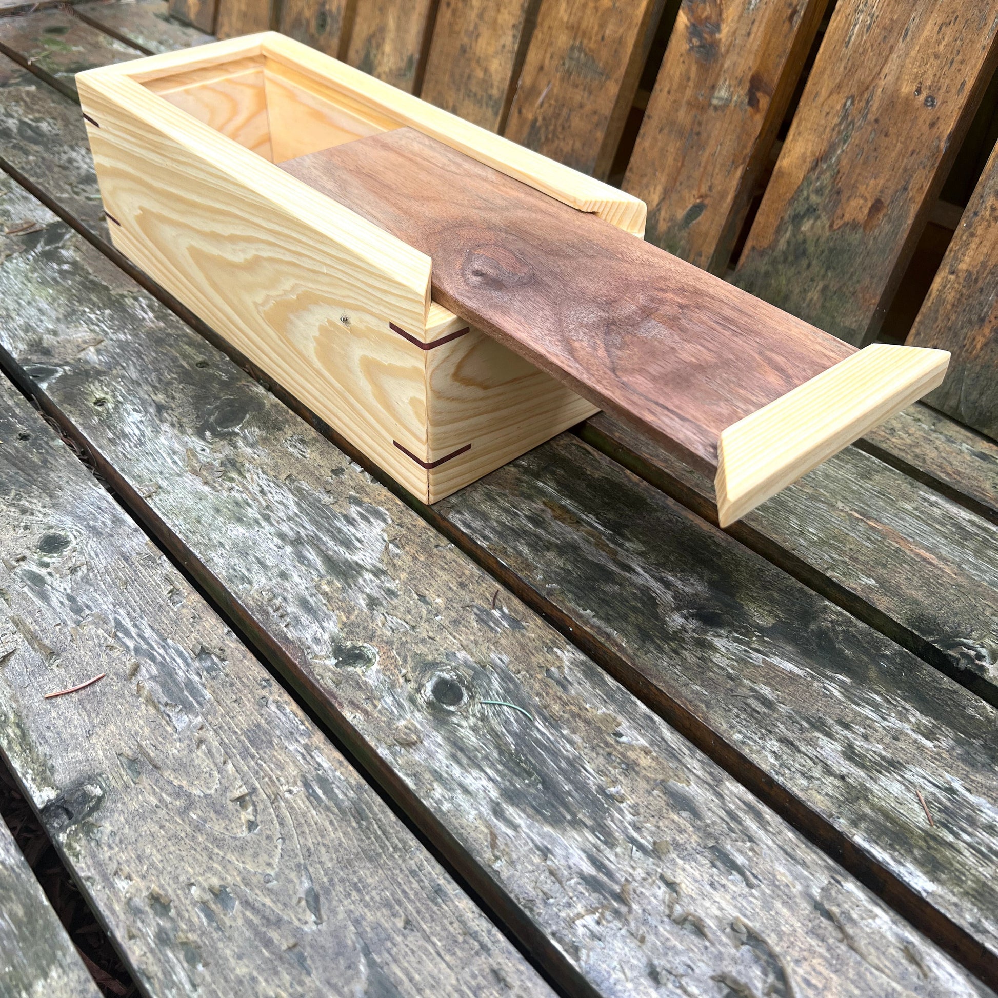 Wooden bird feeder on a wooden surface with a wooden fence in the background