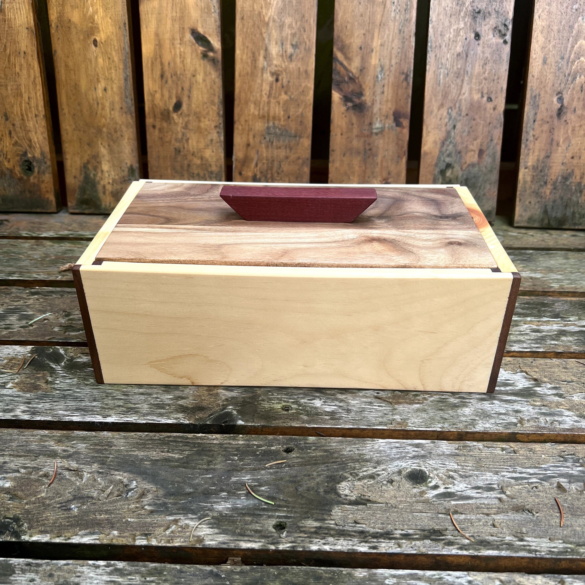 Wooden box with a walnut lid on a wooden surface