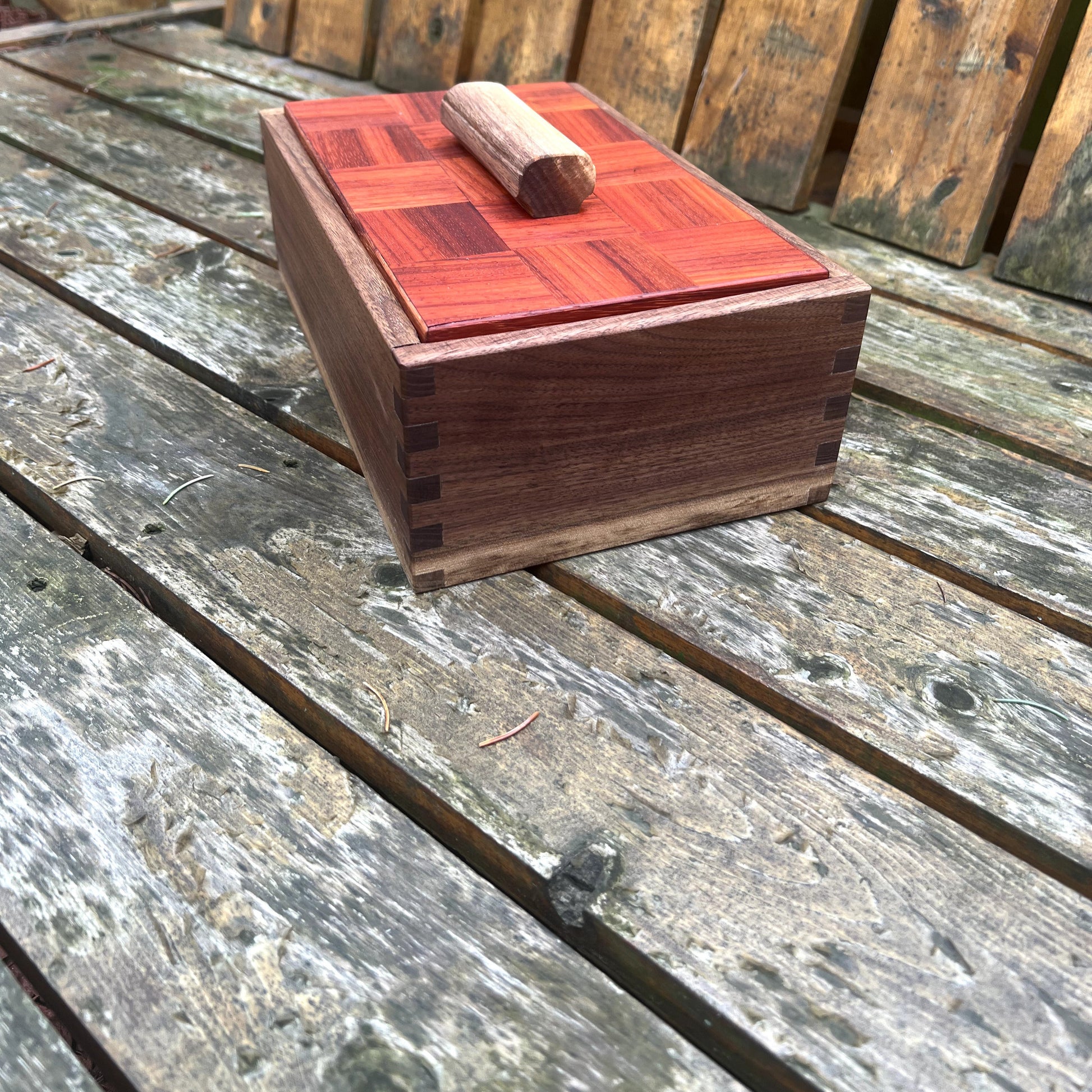 Wooden jewelry box with red top on a wooden surface