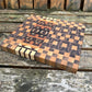 Wooden cutting board with checkered pattern on a wooden surface