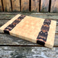 Butcher block cutting board with black and white pattern on a wooden surface