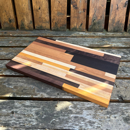 Wooden cutting board with multicolored stripes on a wooden surface